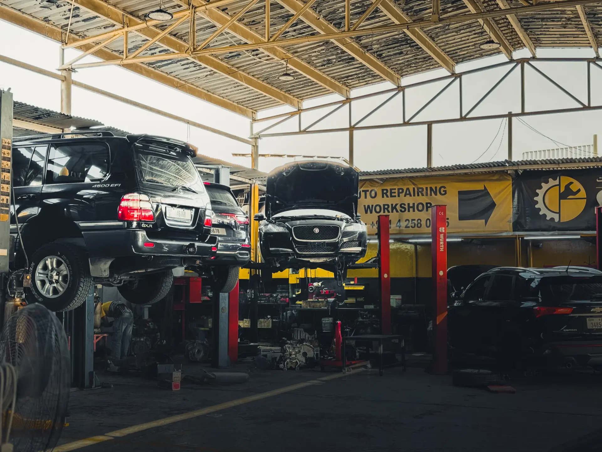 Cars raised on lifts inside the Sunshine Auto car repair workshop in Al Qusais, Dubai