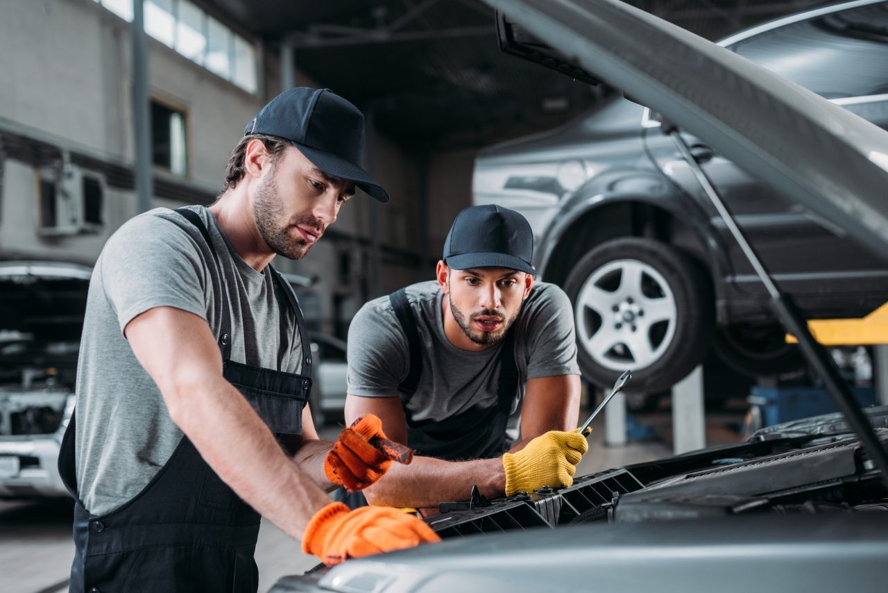 Two mechanics working on a car engine together in a repair workshop